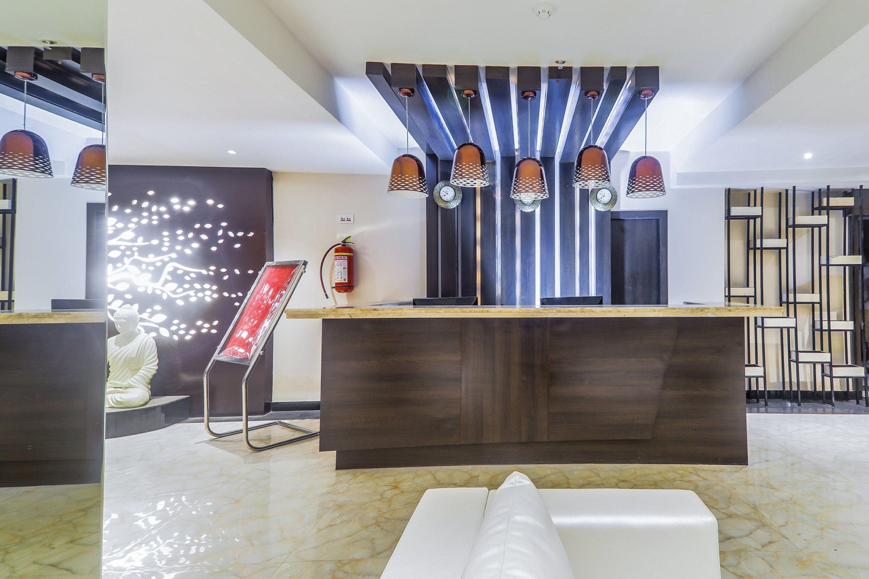 A modern reception area with a marble floor, a reception desk, a fire extinguisher, and a decorative wall piece.