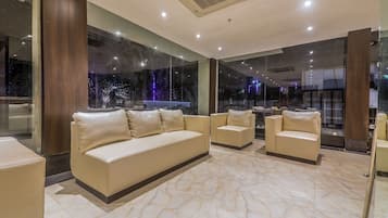 Un moderno vestíbulo de hotel con piso de mármol, sofás de cuero y grandes ventanales que ofrecen vista a la ciudad.