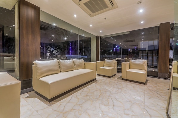 Un moderno vestíbulo de hotel con piso de mármol, sofás de cuero y grandes ventanales que ofrecen vista a la ciudad.