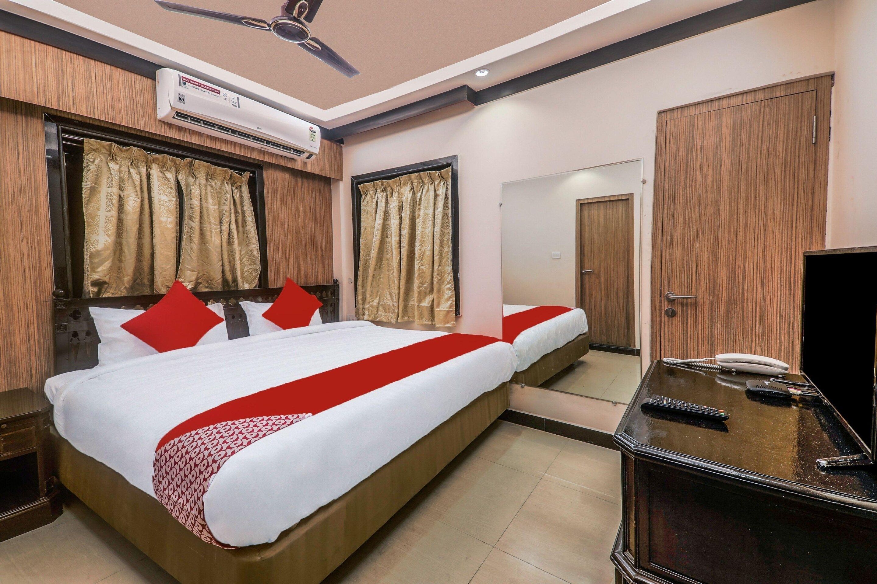 A hotel room with a bed, a desk with a telephone, and a mirror.