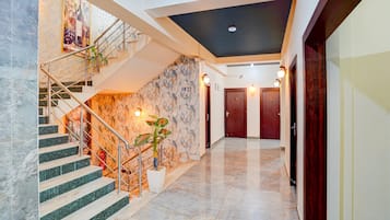 A hotel lobby with a marble staircase, a wall-mounted plant, and a ceiling with recessed lighting.
