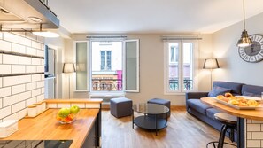 A modern apartment with a kitchen, dining area, and living room. There are two windows with balconies, a sofa, a coffee table, and a lamp. - Paris - Bastille l AC & 10 min from Marais (Paris)