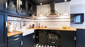 A modern kitchen with dark cabinetry, a black and white checkered floor, a built-in oven, and a wooden countertop. - Paris - Bastille l AC & 10 min from Marais (Paris)