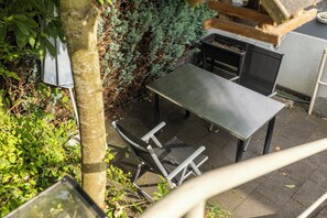 An outdoor seating area with a metal table and chairs, surrounded by greenery and a small garden. - Cozy house surrounded by beautiful nature, with a garden and parking (Obernhof)