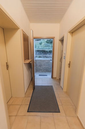 A hallway with a door leading to an outdoor area, a small shelf, and a mat at the entrance. - Cozy house surrounded by beautiful nature, with a garden and parking (Obernhof)