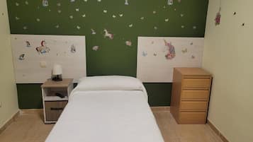 Un dormitorio con una cama, una mesita de noche con lámpara, un aparador y adhesivos con forma de mariposas en la pared.