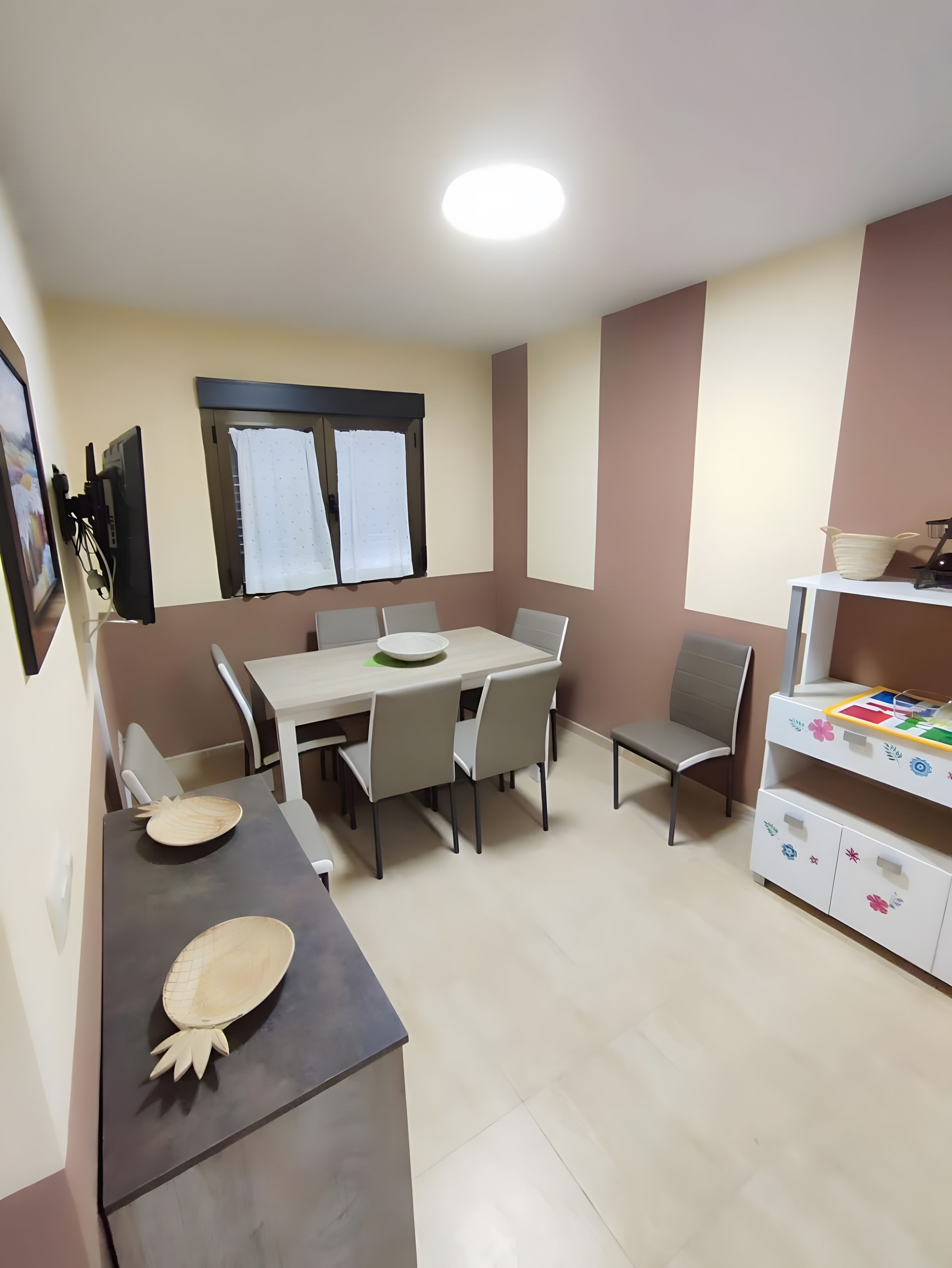 Un comedor con una mesa, sillas y un televisor montado en la pared.