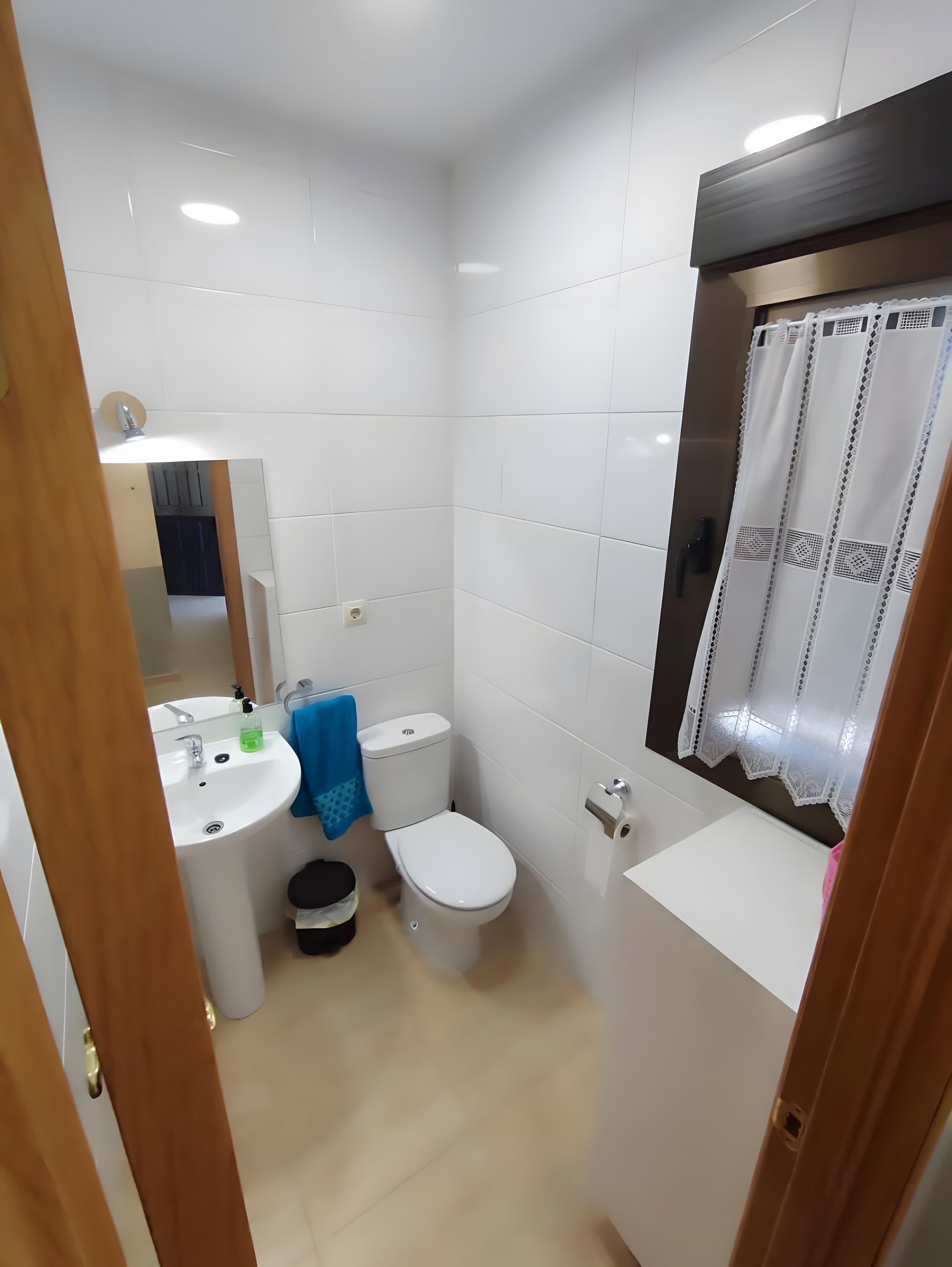 Un baño pequeño y limpio, con inodoro, lavamanos y espejo.