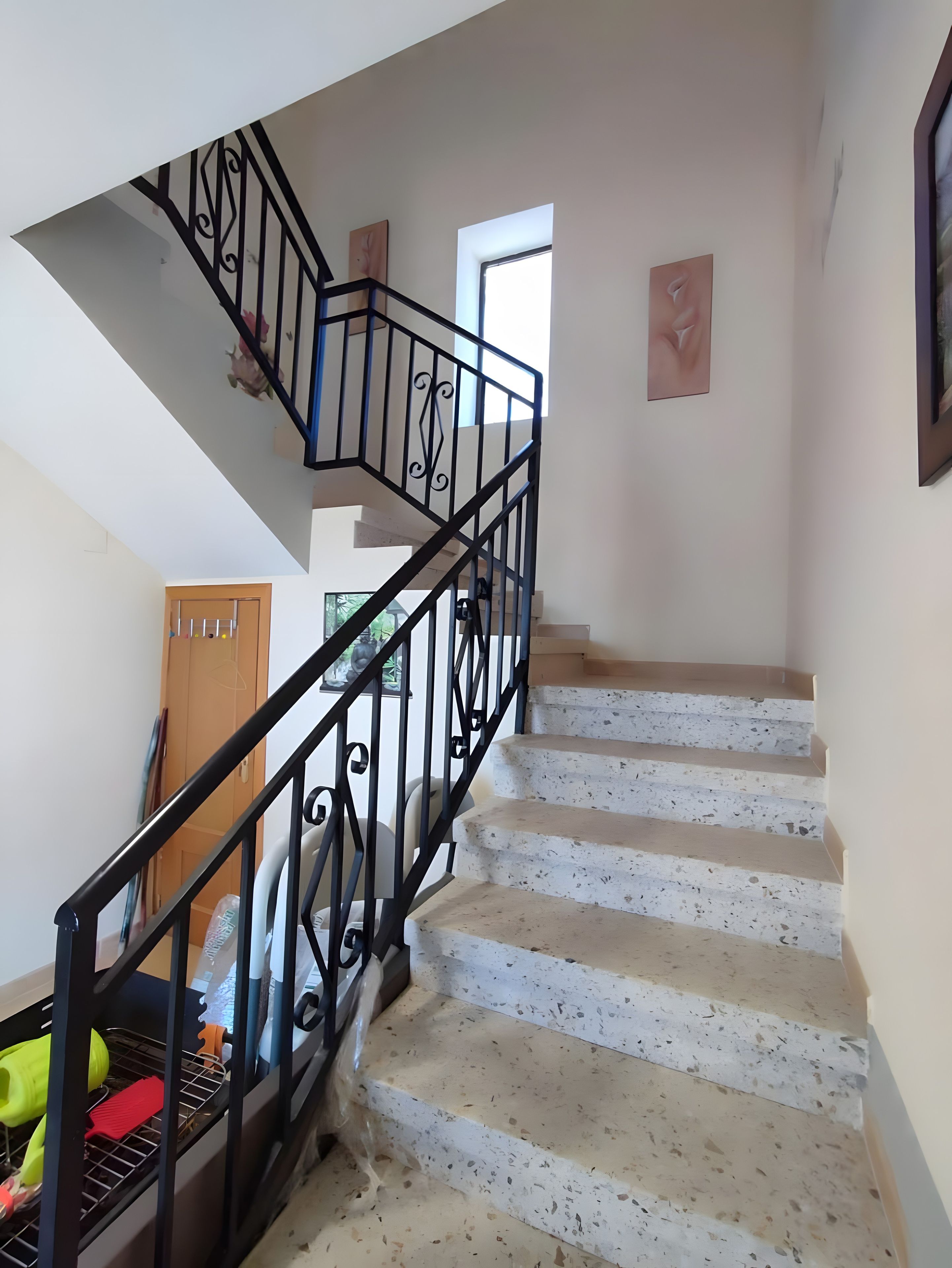 Un escalier avec une rampe et une main courante en métal noir, menant à l’étage supérieur.