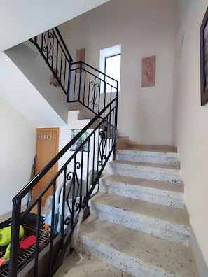Una escalera con barandilla de metal negro y pasamanos que lleva a un piso superior.