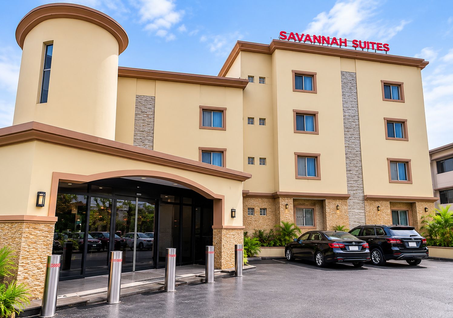 Een hotel met een modern design, met een opvallende entree met een overdekte doorgang, meerdere ramen en een bord waarop 'SAVANNAH SUITES' staat.