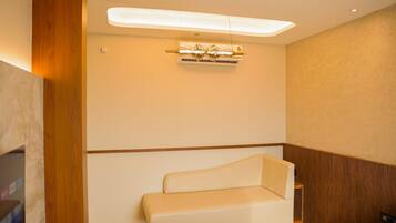 Habitación de hotel moderna con sofá, lámpara de techo y pared decorativa de madera.