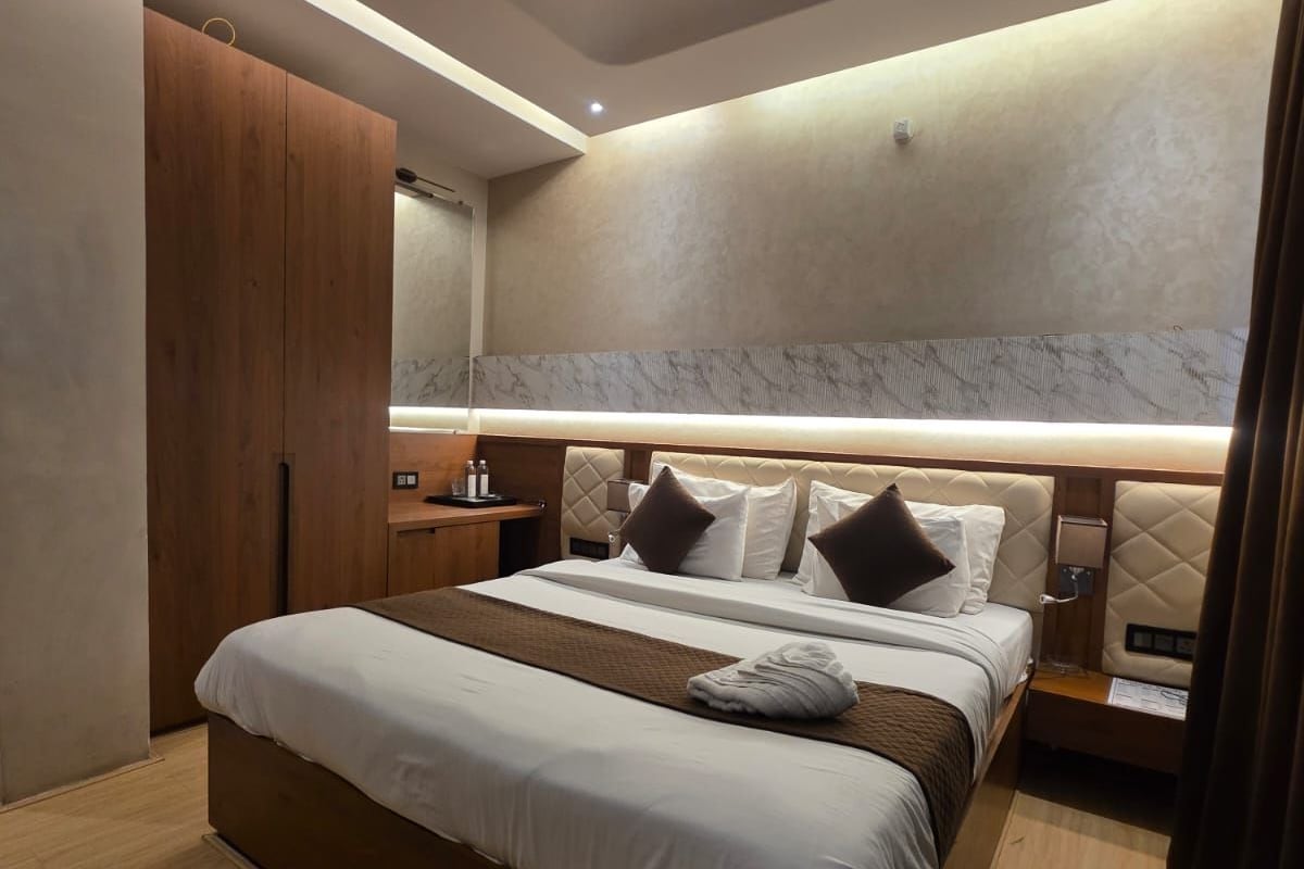 A modern hotel room with a large bed, a ceiling fan, and a marble accent wall.
