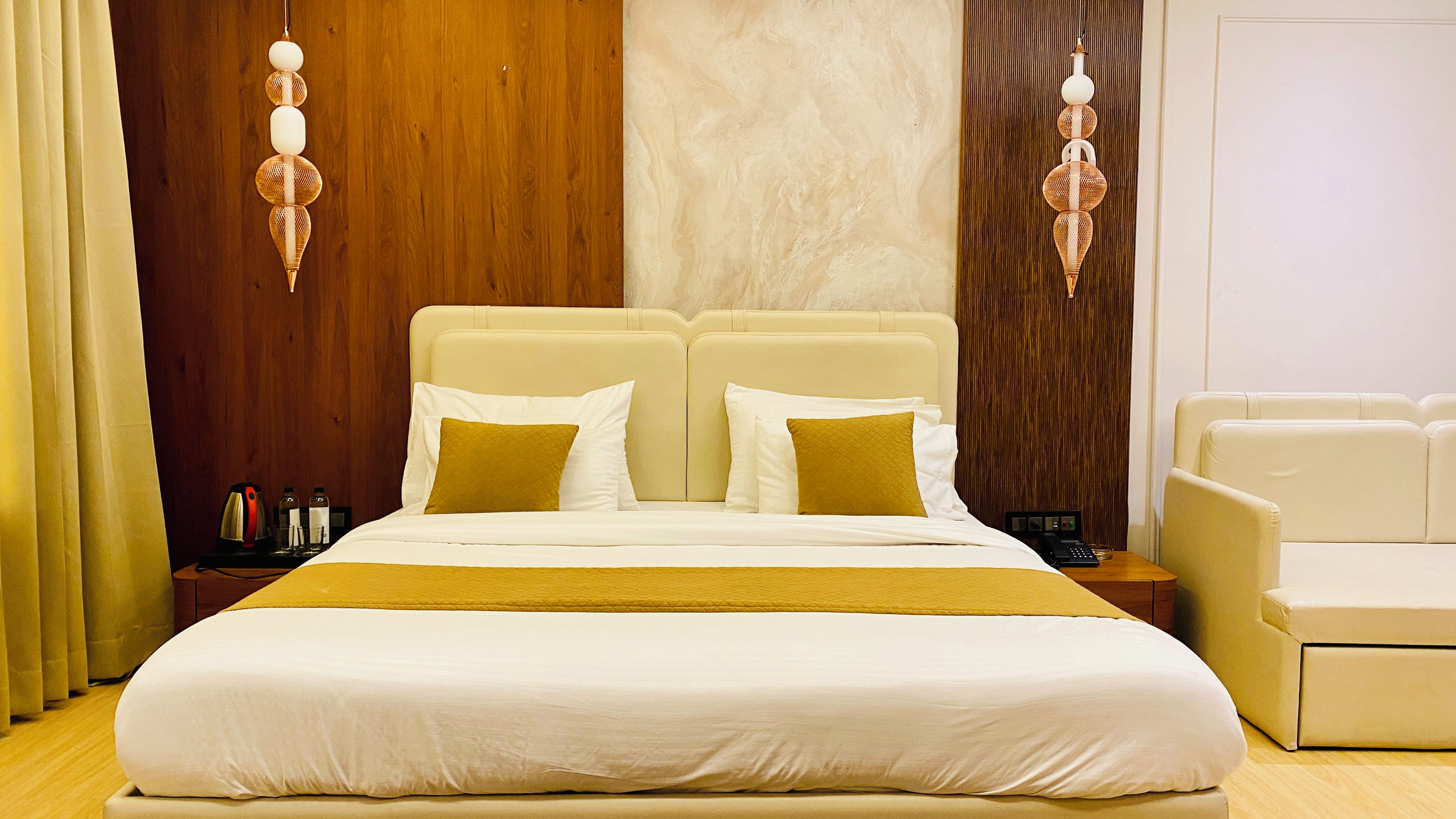 Una habitación de hotel con una cama grande, dos mesitas de noche, una lámpara de noche y una silla.