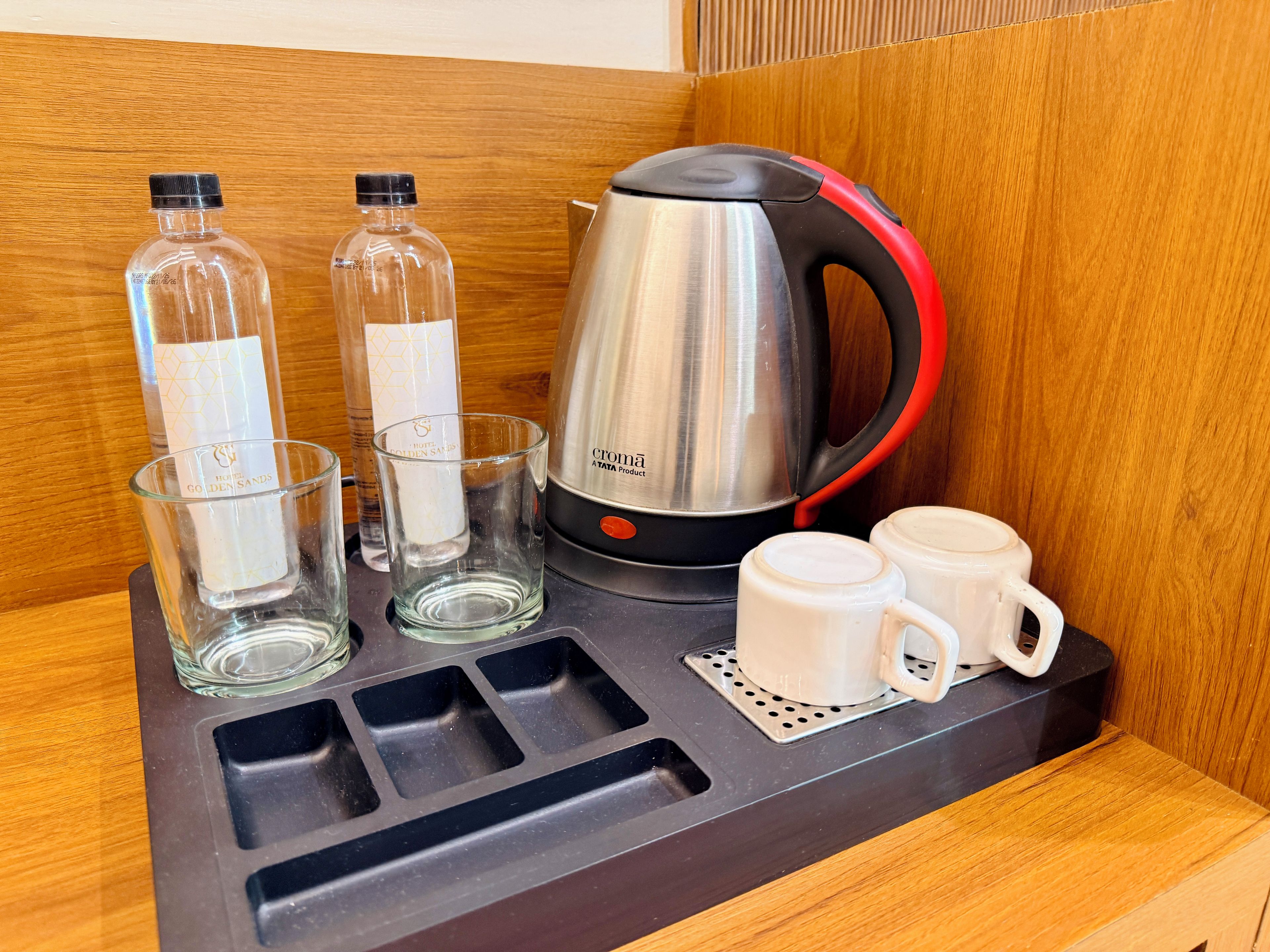 Una estación de café con un hervidor, dos vasos y dos tazas sobre una bandeja.