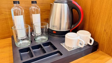 Una estación de café con un hervidor, dos vasos y dos tazas sobre una bandeja.
