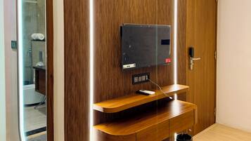 Una habitación moderna con un panel de madera en la pared, televisor integrado y un espejo.