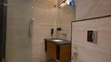 Un baño moderno con cabina de ducha de vidrio, tocador de madera y un inodoro blanco.