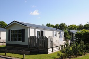Une maison mobile de plain-pied, dotée d’un porche à l’avant et d’une clôture en piquets.