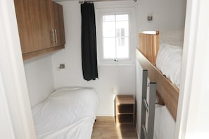 A small, compact room with two single beds, a window, a wooden wardrobe, and a small stool. - Lovely Villetta in the Heart of Texel (Den Burg)
