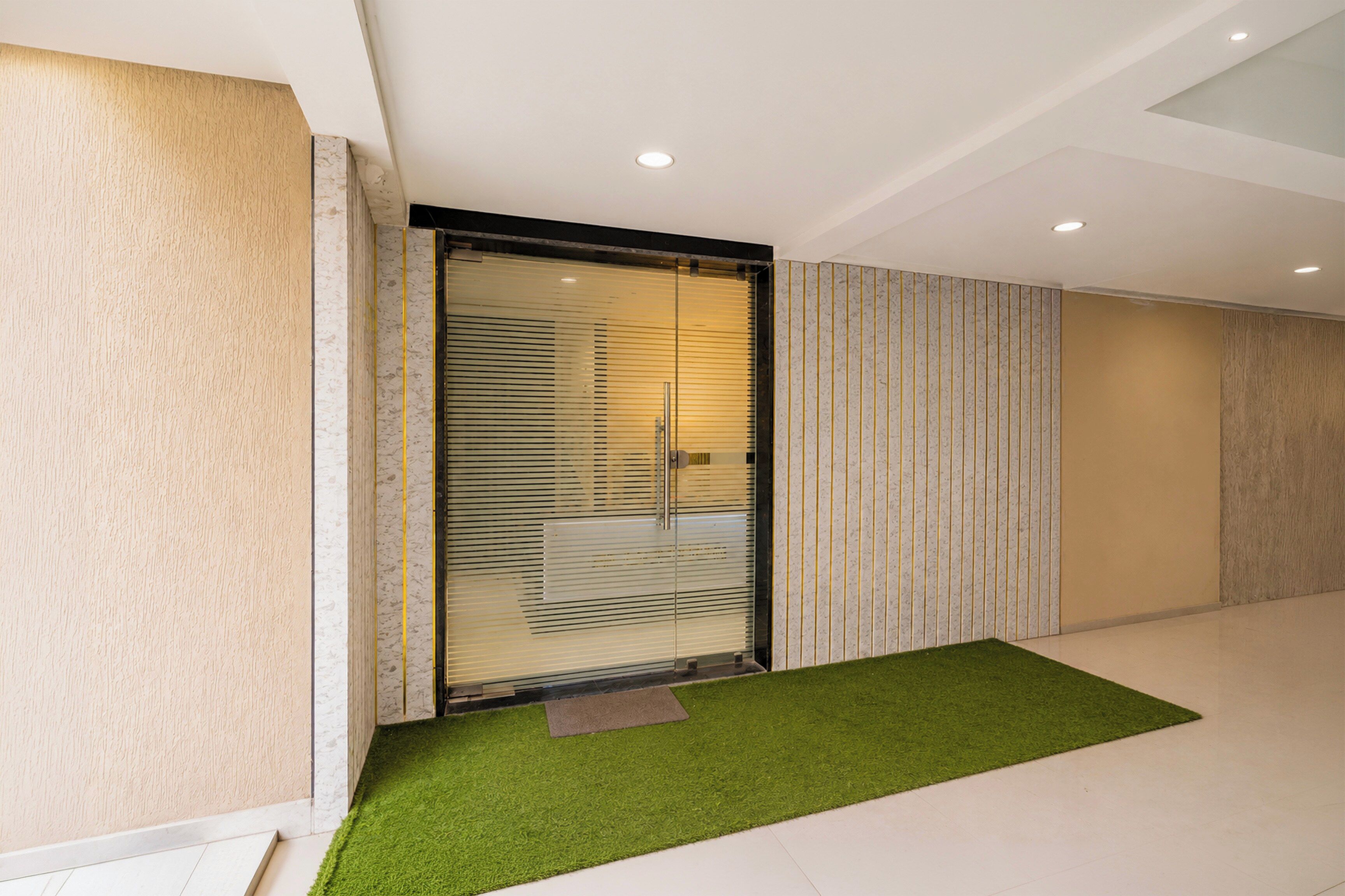 A modern interior with a sliding glass door, a green artificial turf area, and a patterned wall.