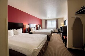 A hotel room with three beds, a television, a desk, and a window with curtains. - Inn America - Boise (Boise)