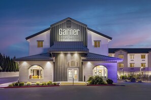 Um hotel chamado 'Garner' com design moderno, apresentando uma entrada marcante e fachada bem iluminada.