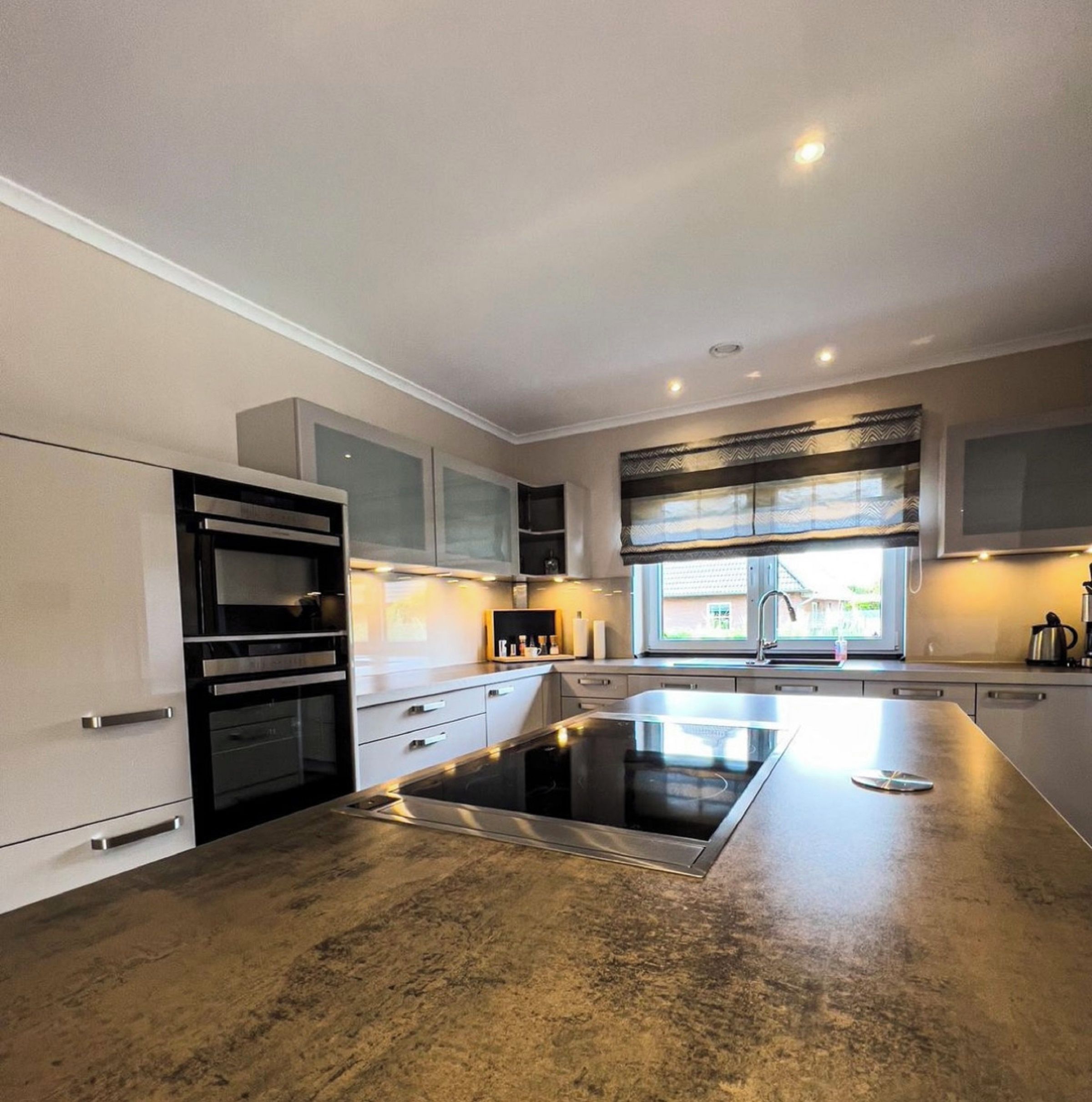 A modern kitchen with a central island, built-in appliances, and a window providing natural light.