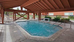 Una piscina interior con una terraza de madera y sillas reclinables.