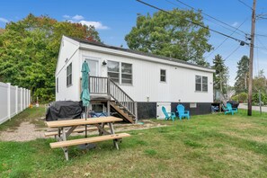 A single-story mobile home with a covered patio area, a wooden deck, and a small outdoor seating area with chairs. - 2/10 of a mile to Long Sands Beach via Webber Road! 2BD/1BA duplex, ( Unit 1) sleeps 6, with in-unit laundry, mini-splits, and a stocked kitchen. Rent both sides for a two-family getaway. Parking for 2, steps from beaches, shops, and dining. (York)