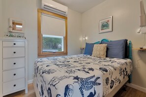 Ein Schlafzimmer mit Bett, Schminktisch, Fenster und Wanddekorationen.