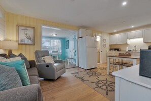 Ein modernes Wohnzimmer mit Sofa, Sessel und einem Essbereich mit Tisch und Stühlen.