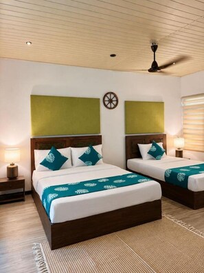 A hotel room with two beds, a ceiling fan, and a wall clock. - Nest Villas | Your peaceful stay in Colombo 7 (Colombo)