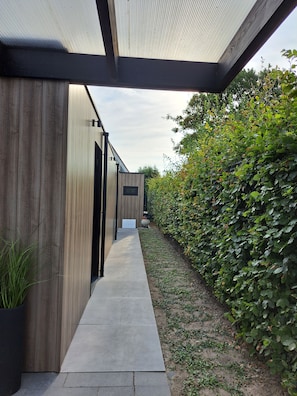 A modern building with a covered walkway, wooden siding, and a signboard.