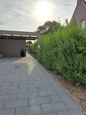 A paved pathway leading to a building with a wooden facade and a covered entrance. - Adorable 1-bedroom cottage with AC in charming Dishoek (Koudekerke)