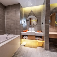Un baño moderno con bañera, lavabo doble y espejo con luces.
