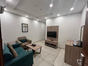 A modern living room with a sofa, a coffee table, a TV stand, and a cabinet. - Tu Jardin Al Harmain Jeddah (Jeddah)