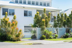 A two-story residential building with a white exterior, multiple windows, and a gated entrance. - "Bluewater" – Pool at home, Beach just beyond (North Avoca)