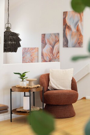 A modern living room with a brown armchair, a round side table with a plant, and a hanging lamp. - "Bluewater" – Pool at home, Beach just beyond (North Avoca)