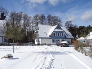 A two-story house with a snow-covered roof and a car parked in front. - Comfortable vacation rental for up to 4 people, 2 bedrooms, quiet, green setting, west-facing terrace, Wi-Fi, 4-star DTV (Ostseebad Prerow)