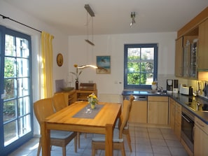 A modern kitchen with a dining table, chairs, and a window. - Comfortable vacation rental for up to 4 people, 2 bedrooms, quiet, green setting, west-facing terrace, Wi-Fi, 4-star DTV (Ostseebad Prerow)