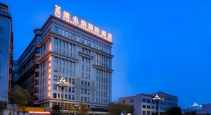 A multi-story building with illuminated signage, a prominent entrance, and a corner location. - Vienna International Hotel (Quanzhou)