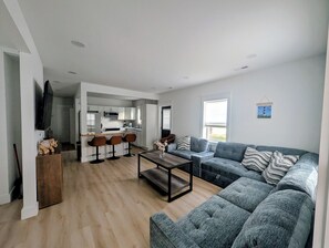 Un salon moderne avec un canapé gris, une table basse et un téléviseur.