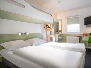 Une chambre d’hôtel avec deux lits, un bureau, une chaise, un miroir et un téléviseur.