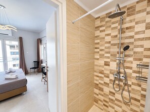 Une salle de bain moderne avec douche, un lit et un coin repas.