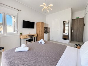 Une chambre d’hôtel équipée d’un lit, d’un bureau, d’une télévision, d’une armoire et d’un miroir dans la salle de bain.