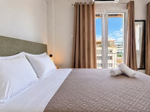Une chambre d’hôtel avec un lit, des rideaux et une vue sur les bâtiments par la fenêtre.