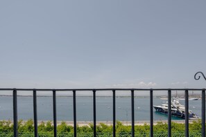 Vista d'un port esportiu amb iots amarrats, cel blau i una costa llunyana.