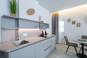 Una cucina moderna con lavello integrato, macchina del caffè e pensile in vetro.