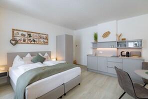 A modern hotel room with a bed, bedside table, and a small kitchenette. - Cozy apartment with a balcony and a view of the garden. (Semmering-Kurort)